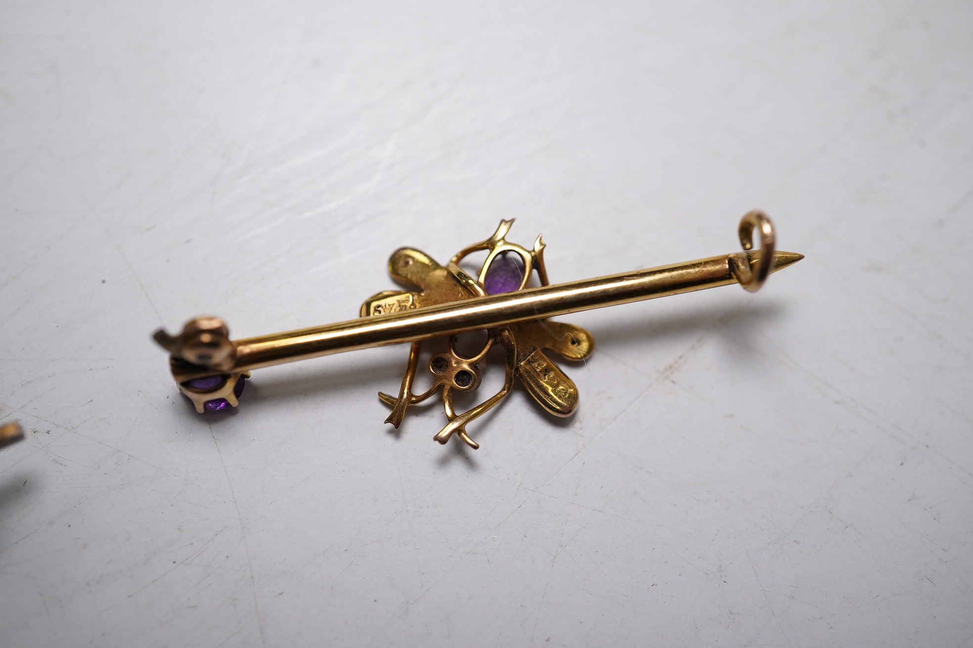 An Edwardian 375, amethyst and seed pearl set bug bar brooch, 39mm (lacking pin) and a yellow metal, garnet? and diamond chip set bar brooch, gross weight 4.4 grams. Condition - poor to fair